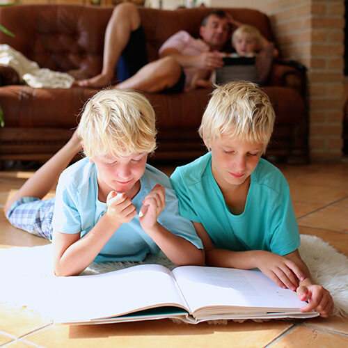 Kids reading book laying on tile floor | Howmar Carpet Inc