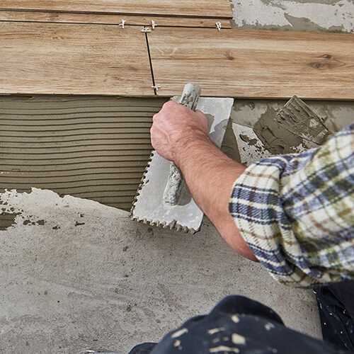 Worker installing tiles on the floor | Howmar Carpet Inc