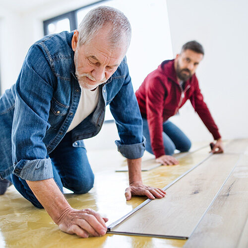 Two men laying vinyl flooring | Howmar Carpet Inc