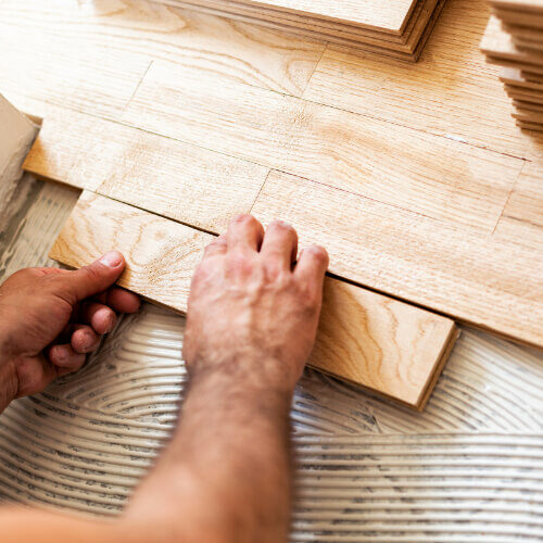 Man installing hardwood flooring | Howmar Carpet Inc