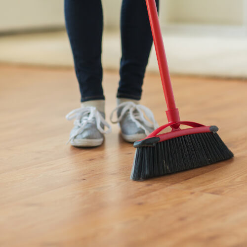 Person sweeping laminate flooring | Howmar Carpet Inc