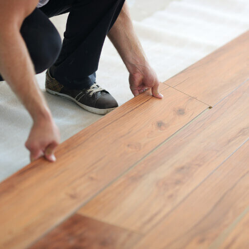 Worker installing laminated flooring | Howmar Carpet Inc